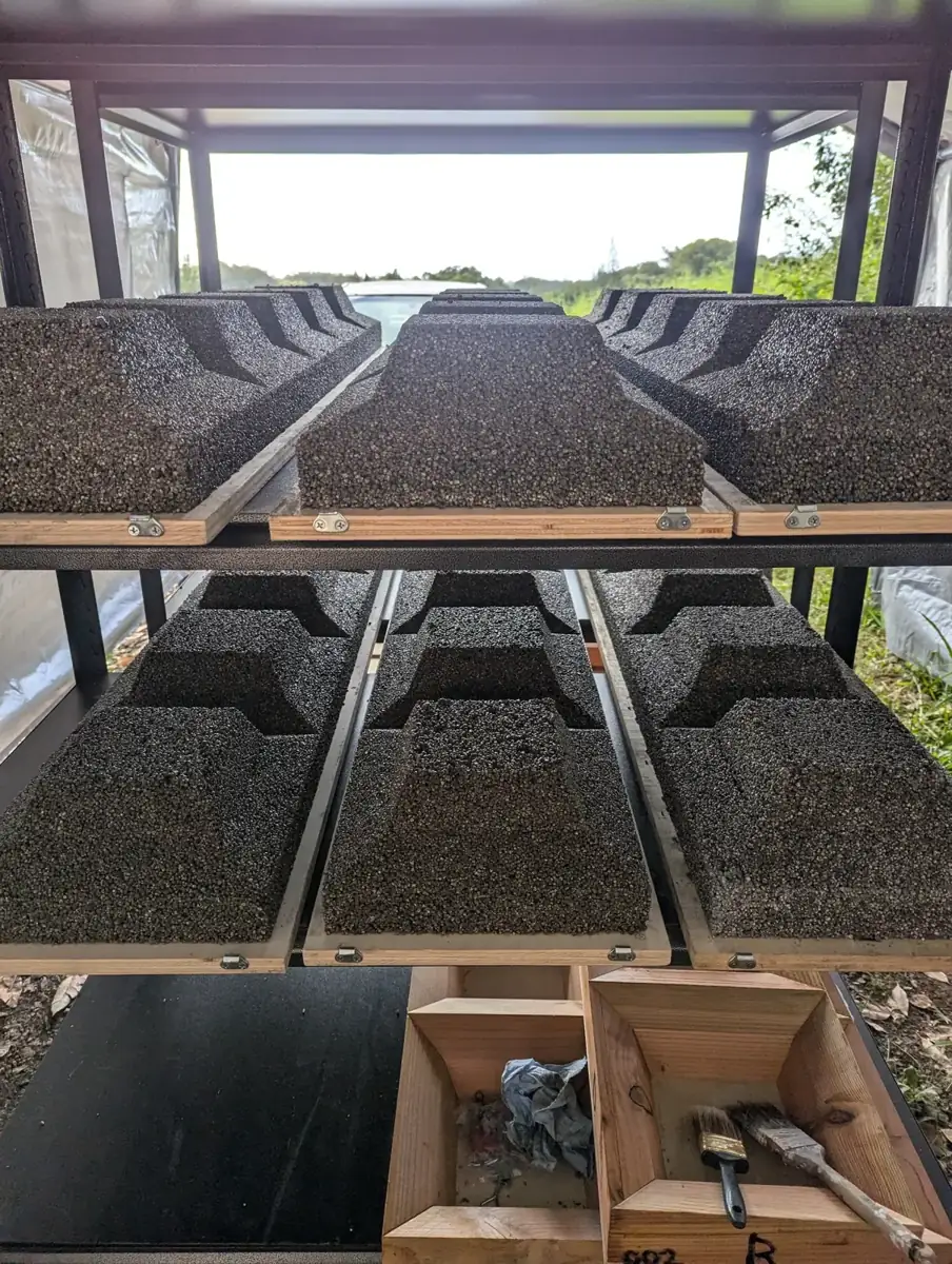 Freshly cast blocks curing on wooden racks in a tent